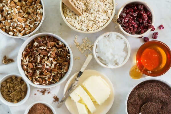 Baking ingredients laid out: nuts, oats, butter, honey, and cocoa