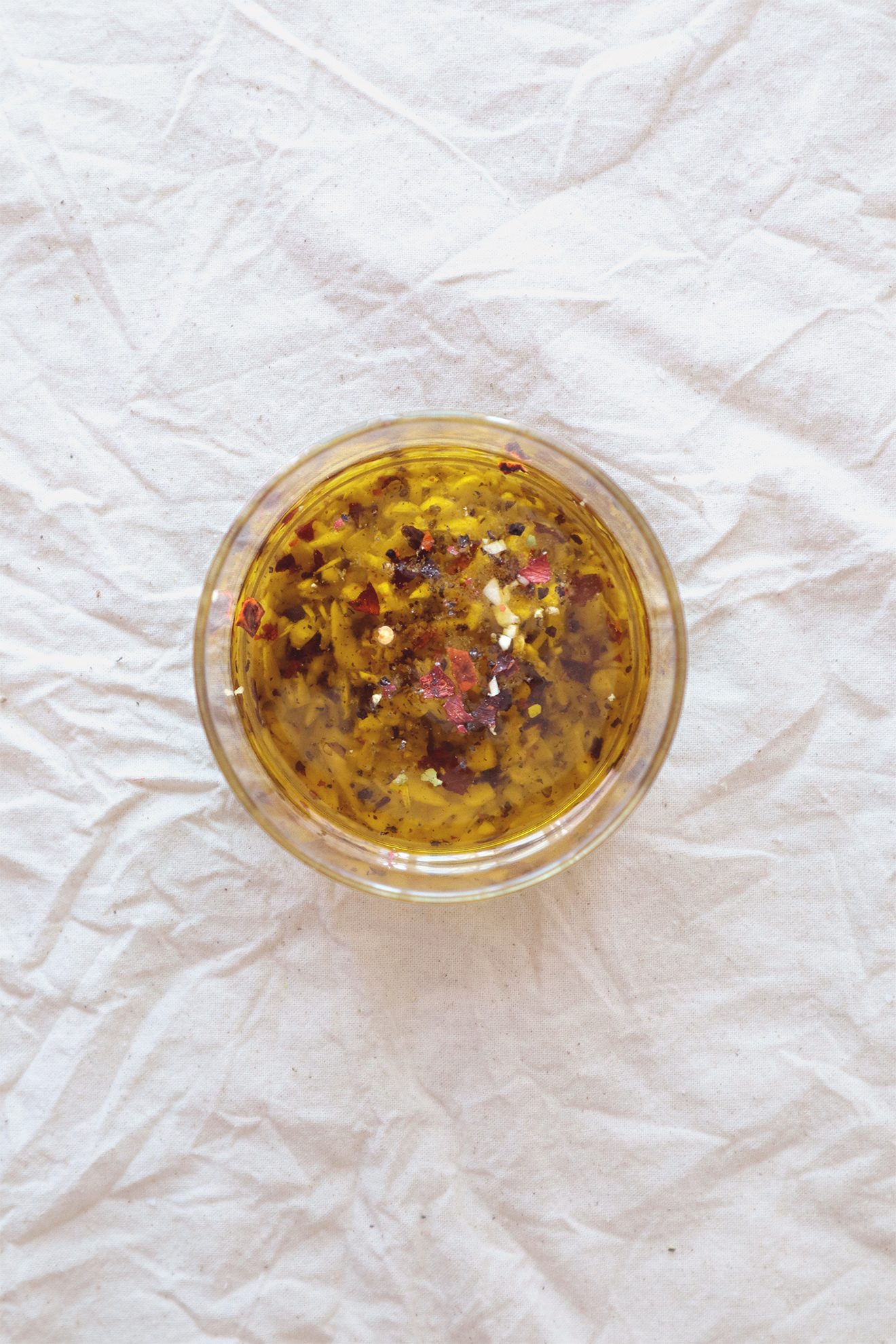 Overhead view of garlic oil mixing in a glass jar